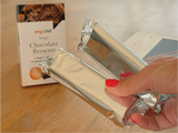 Eine Frau hält 2 verpackte myLINE Chocolate Brownie Riegel zur gesunden Gewichtsreduktion in der Hand.