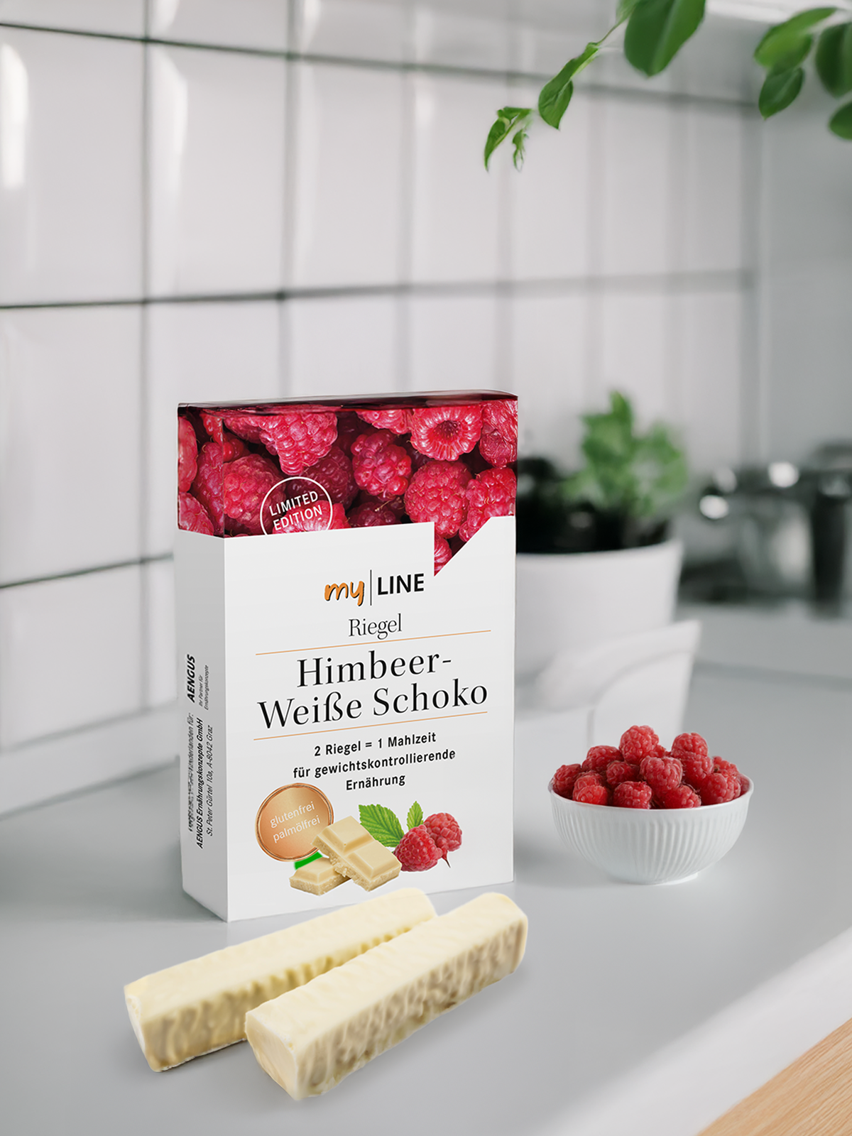 1 Packung myLINE Riegel Himbeer-Weiße Schoko neben Himbeeren und weißem Riegel in der Küche